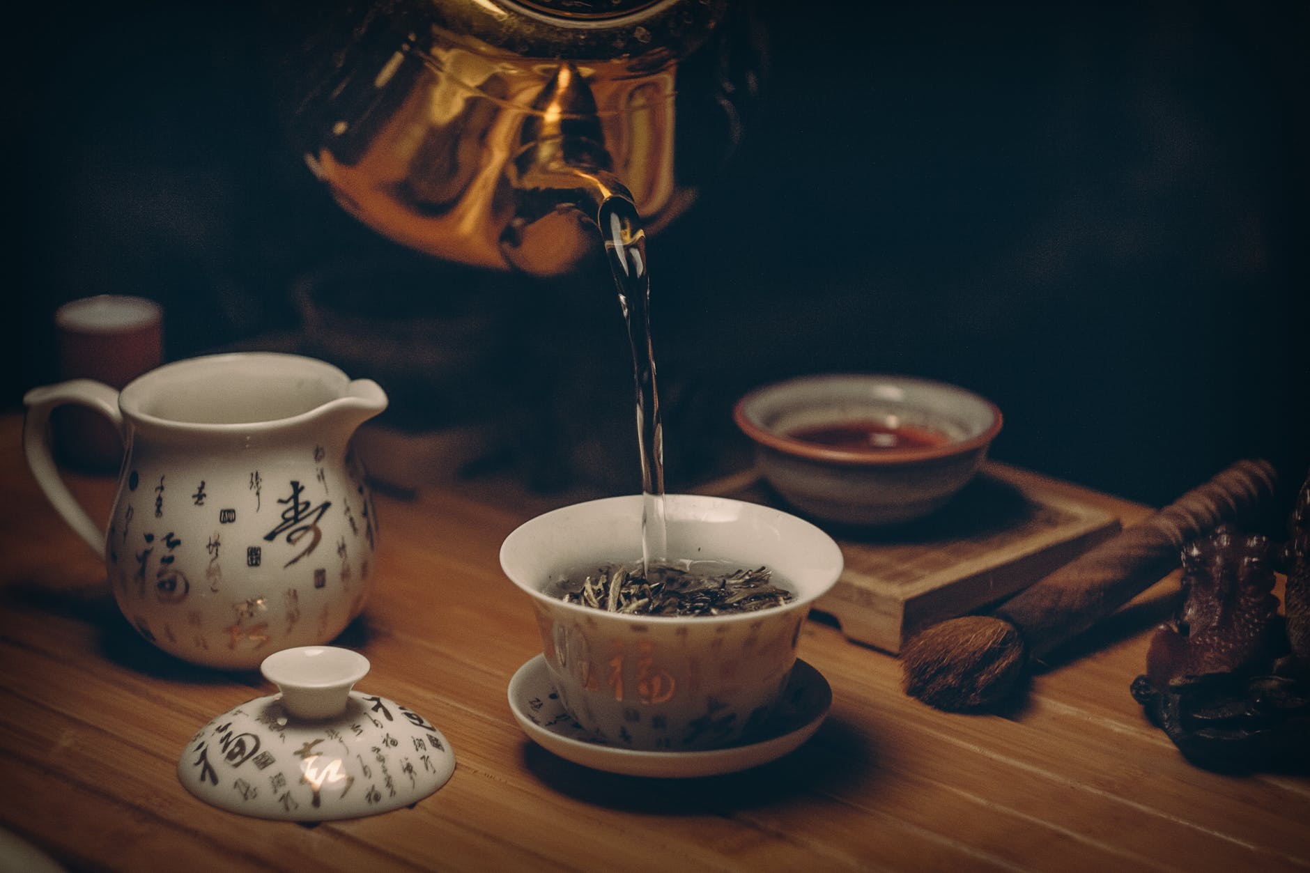 gold kettle pouring hot water for a cup of green tea with lemon
