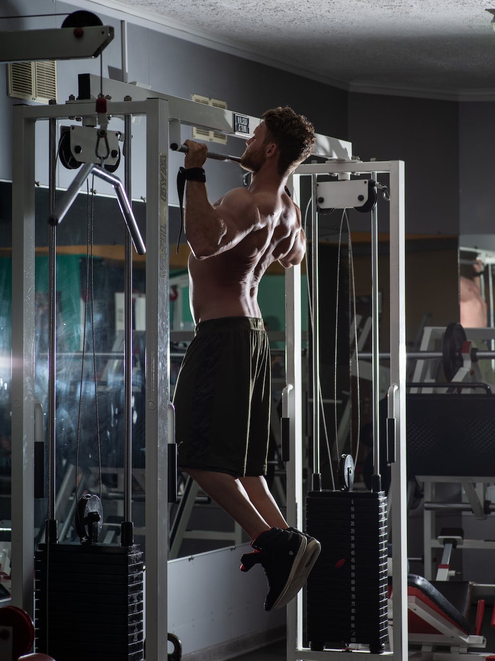 muscular sportsman doing pull up exercise in gym